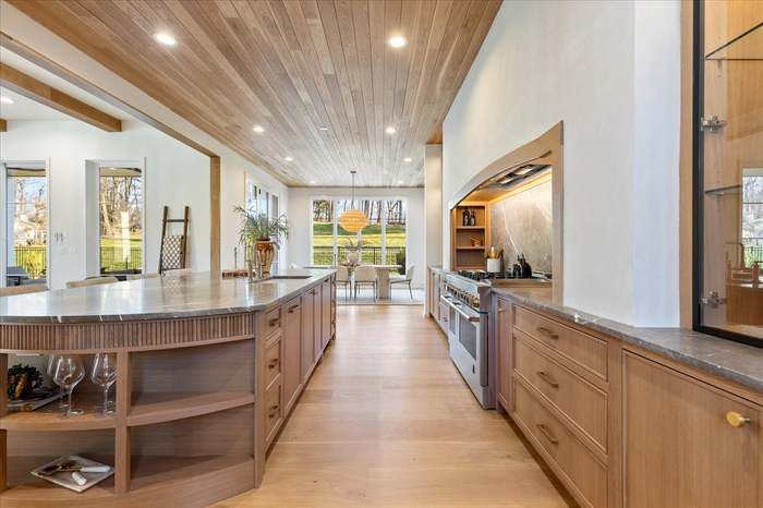 A kitchen with wooden cabinets , granite counter tops , stainless steel appliances and a large island.