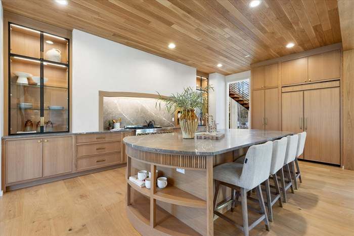 A kitchen with a large island and chairs in it.