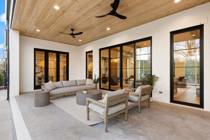 A large patio with a couch and chairs and a ceiling fan.