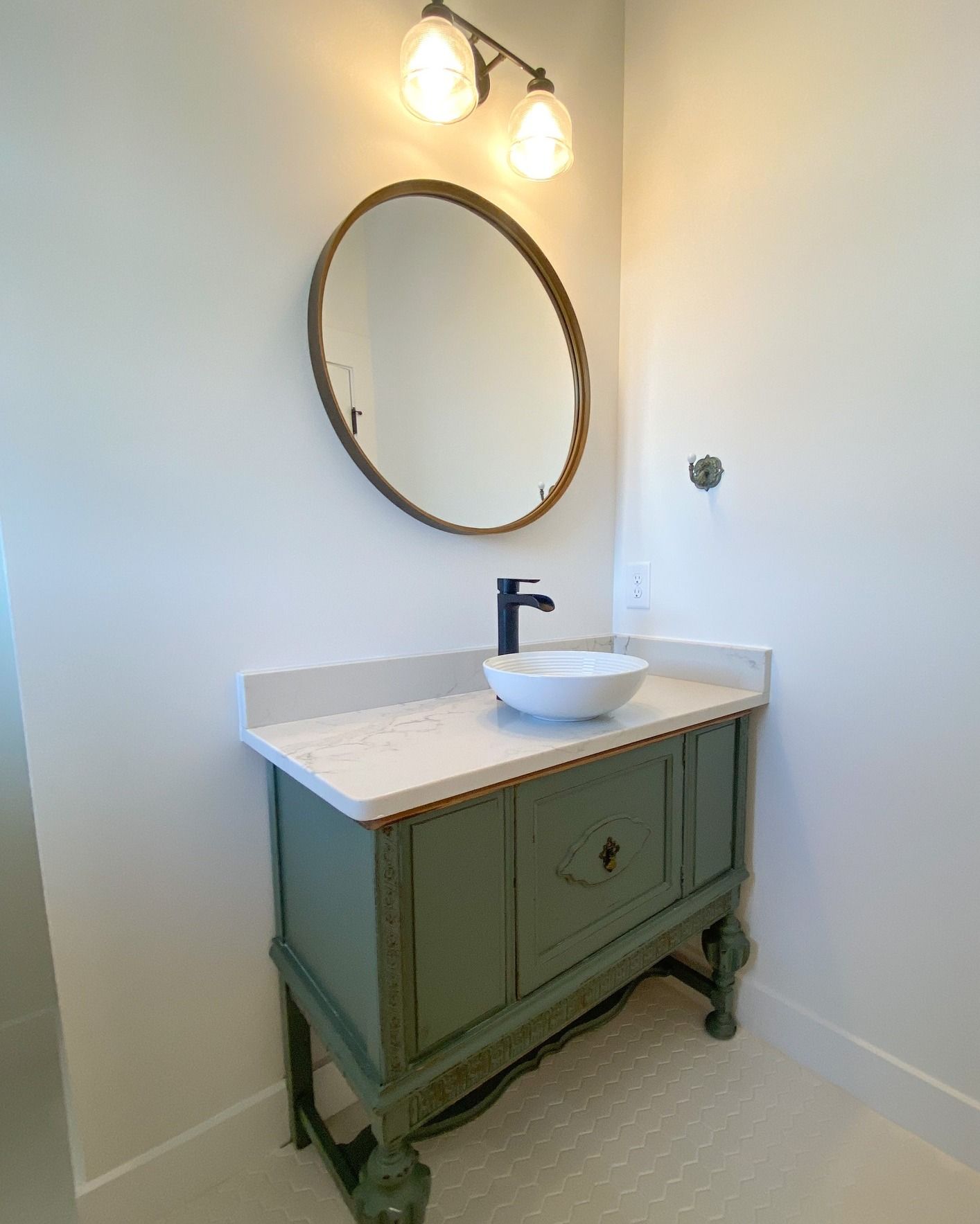 Bathroom with a white double vanity, black fixtures, and black and white tiled floor.