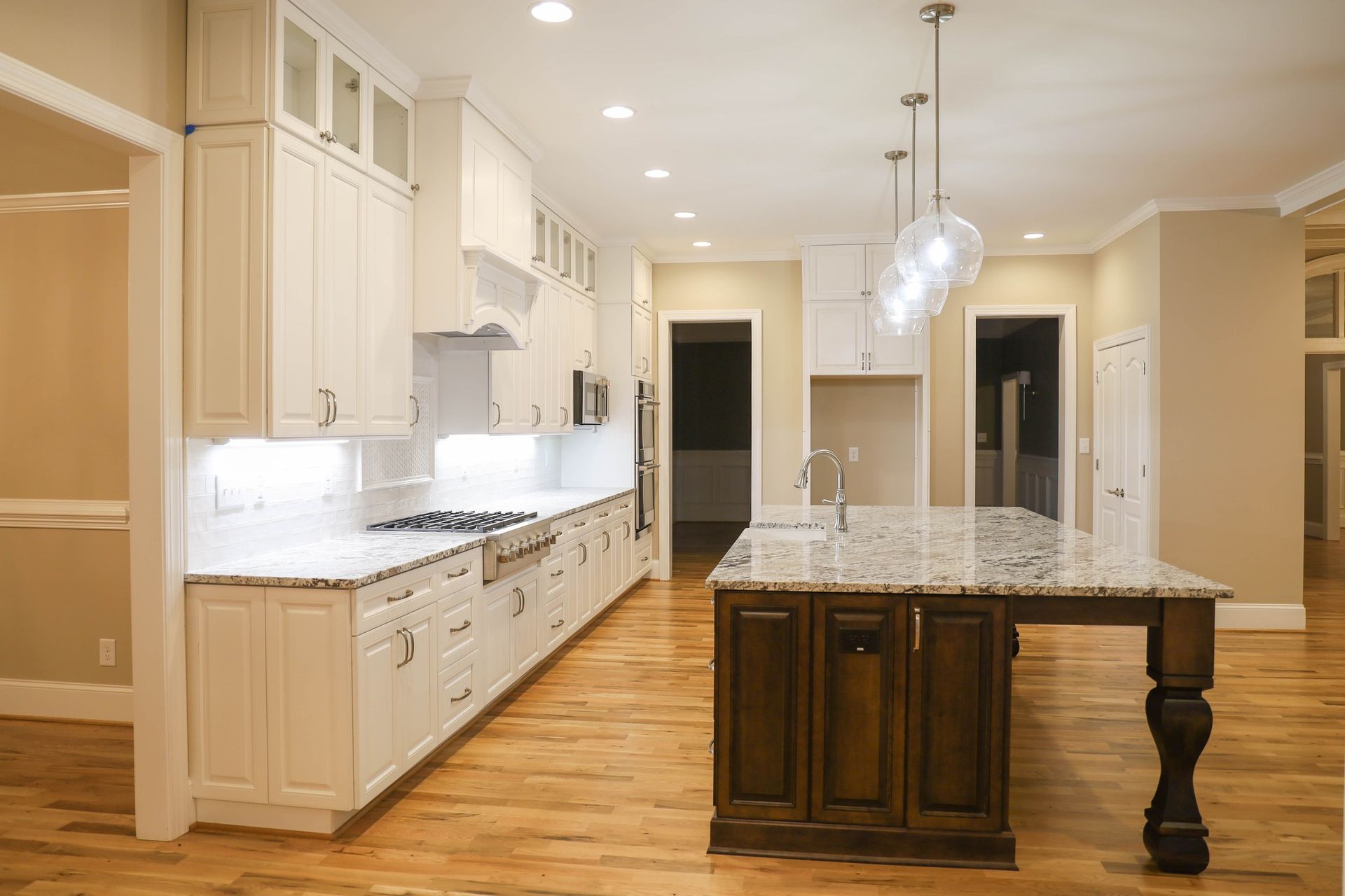 Modern kitchen with white cabinets, dark gray island, and light wood floors.