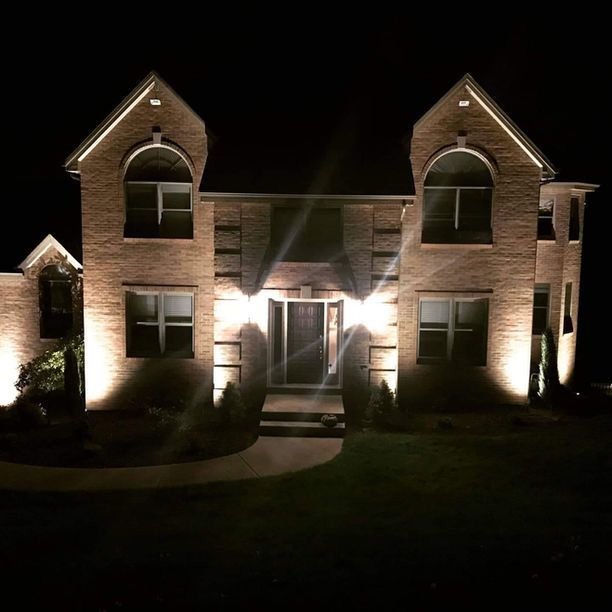 Night-lit brick suburban house with twin gables and a front walkway