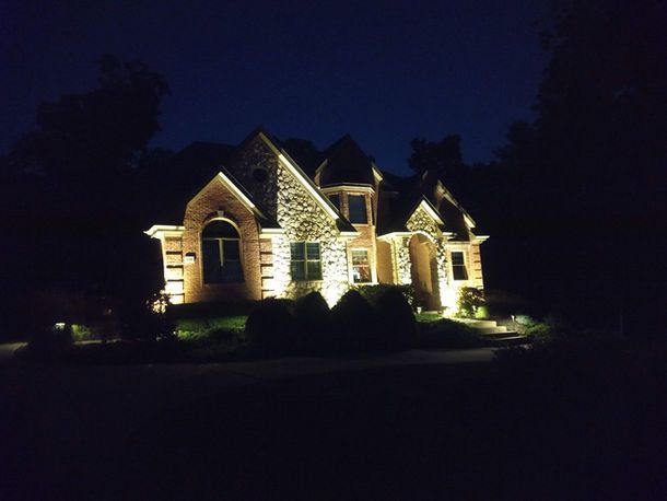 Well-lit stone house at night with warm exterior lighting and dark sky
