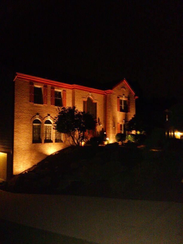 Illuminated brick house at night with warm orange lighting and dark sky