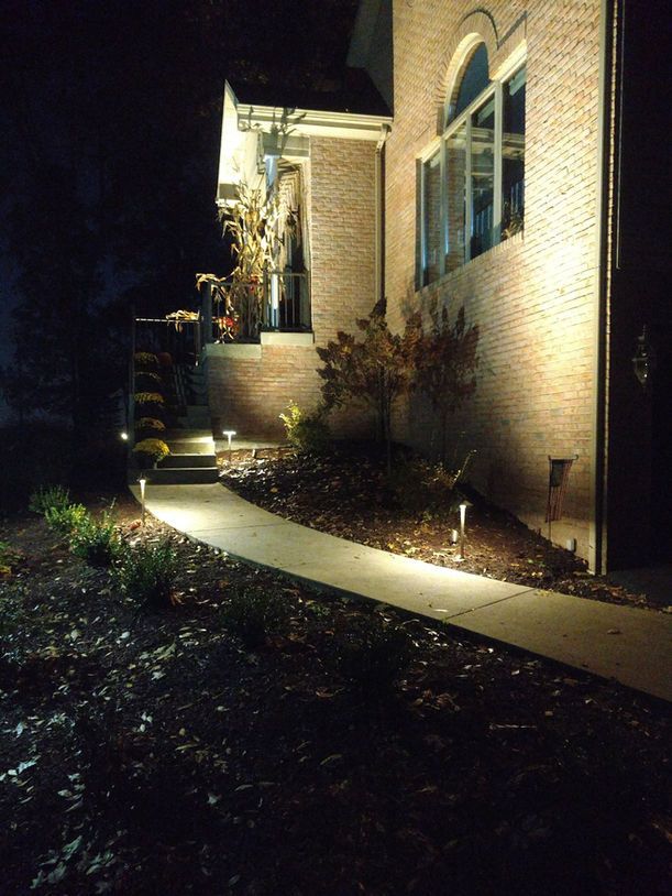 Night-lit brick house with a curved walkway and lit entrance steps.