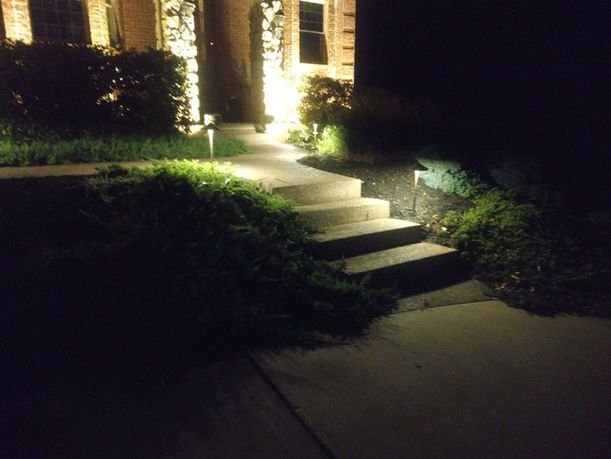 Lit front steps and walkway leading to a house at night