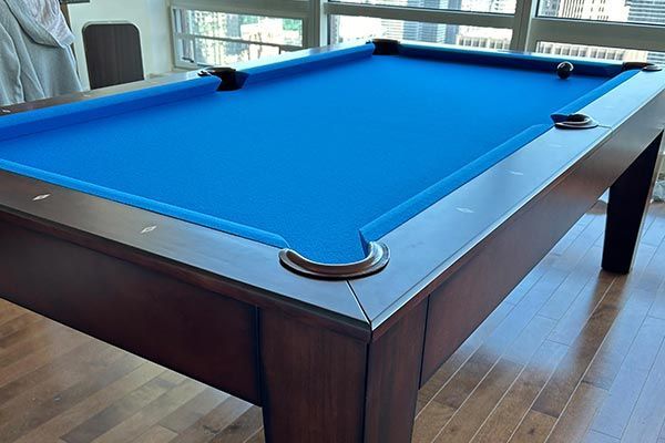 A pool table with a blue cloth and a wooden frame
