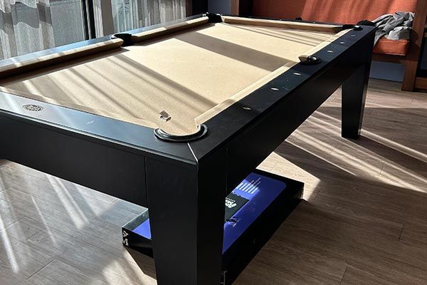 A pool table is sitting on a wooden floor in a living room.