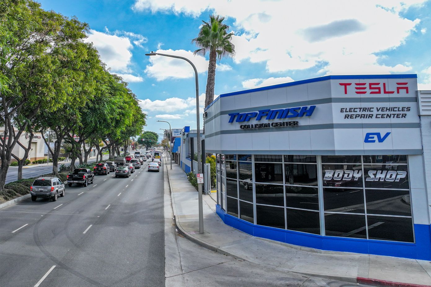 Top Finish auto body shop with Tesla signage on a city street.