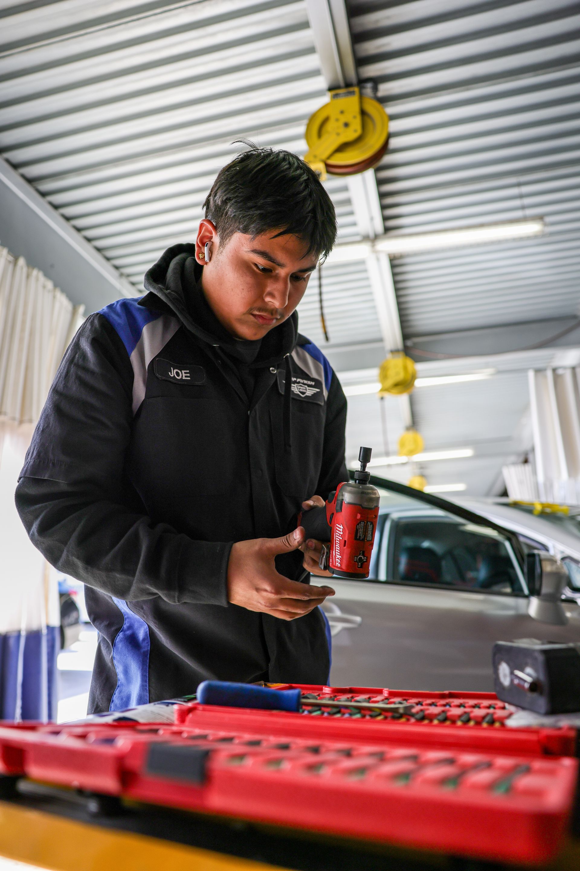 A black truck is parked under a red roof in a garage.