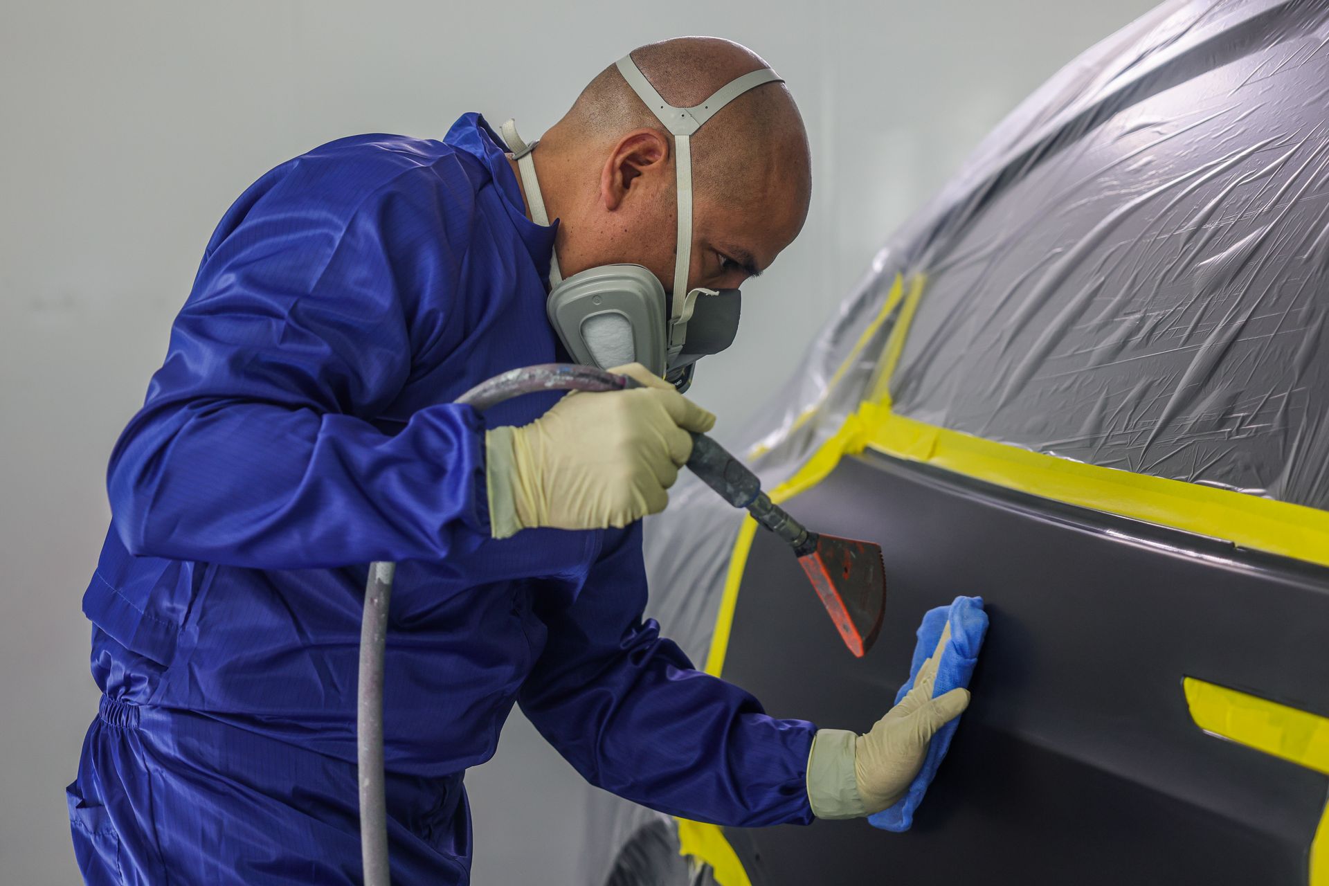A car door is being painted in a paint booth.