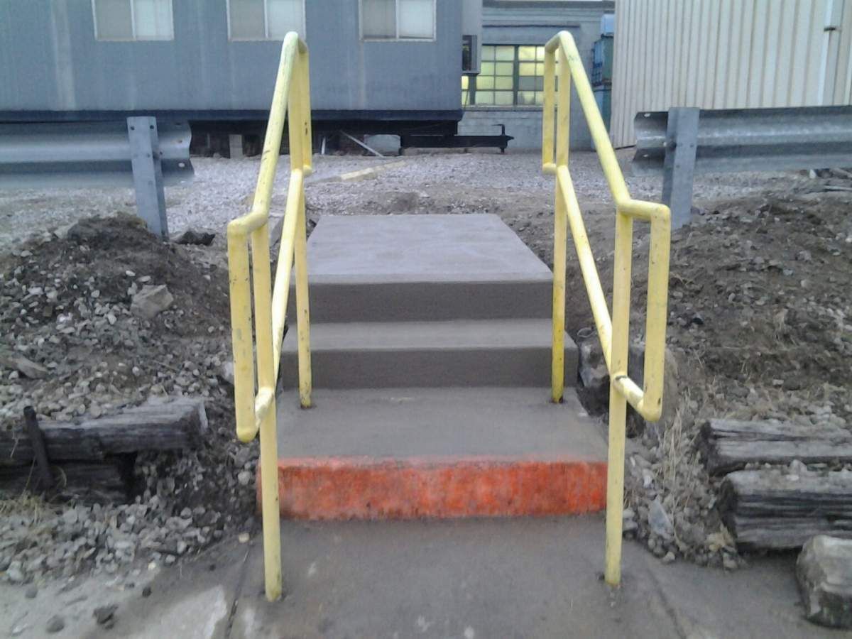 Concrete steps with yellow handrails outside a building.