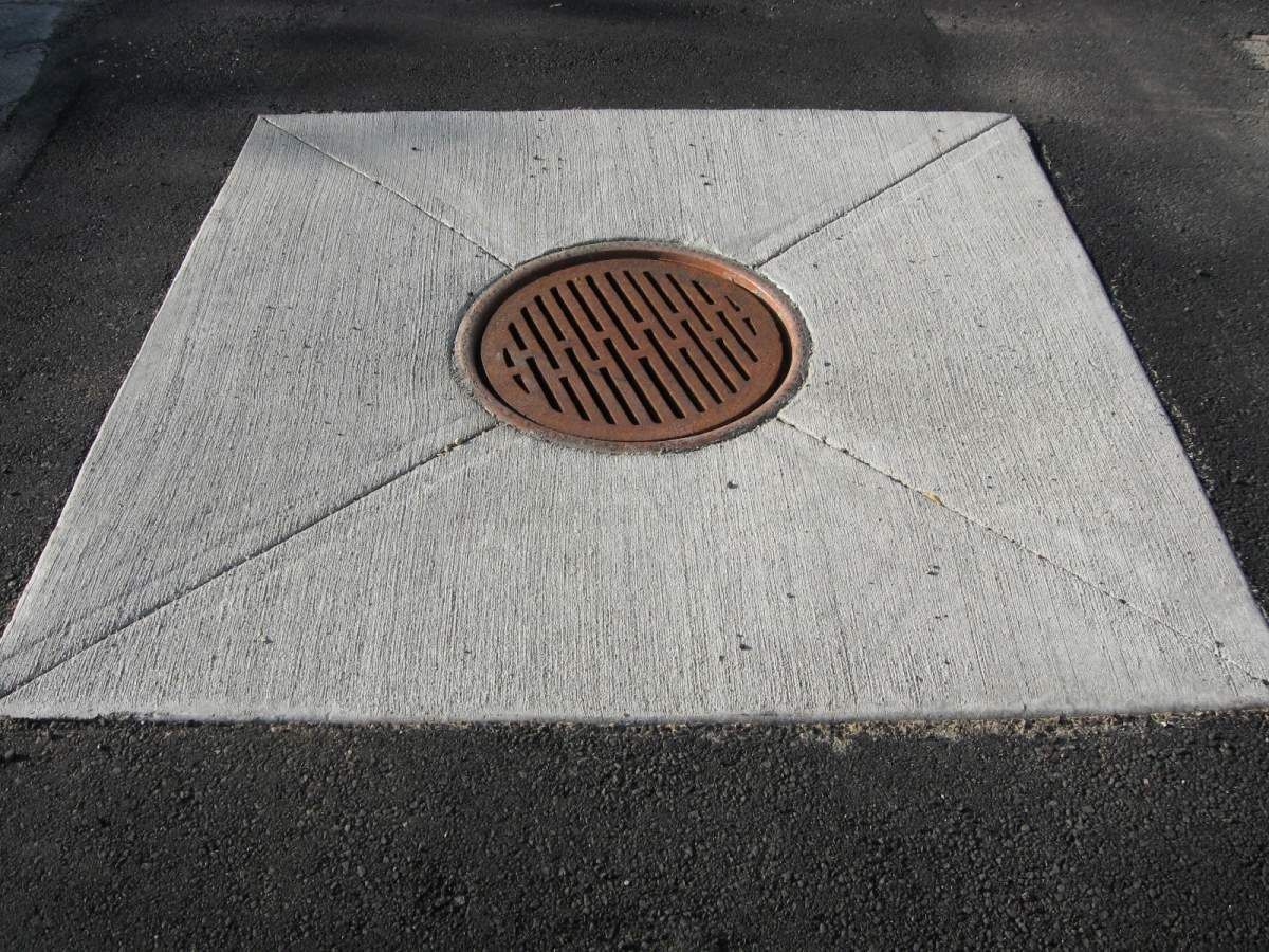 Newly poured concrete curb along a curved driveway; worker in background.