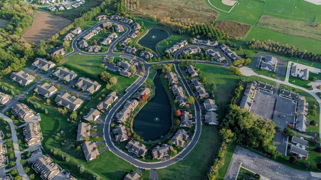 Aerial view of a residential neighborhood with curved roads, ponds, and green spaces.