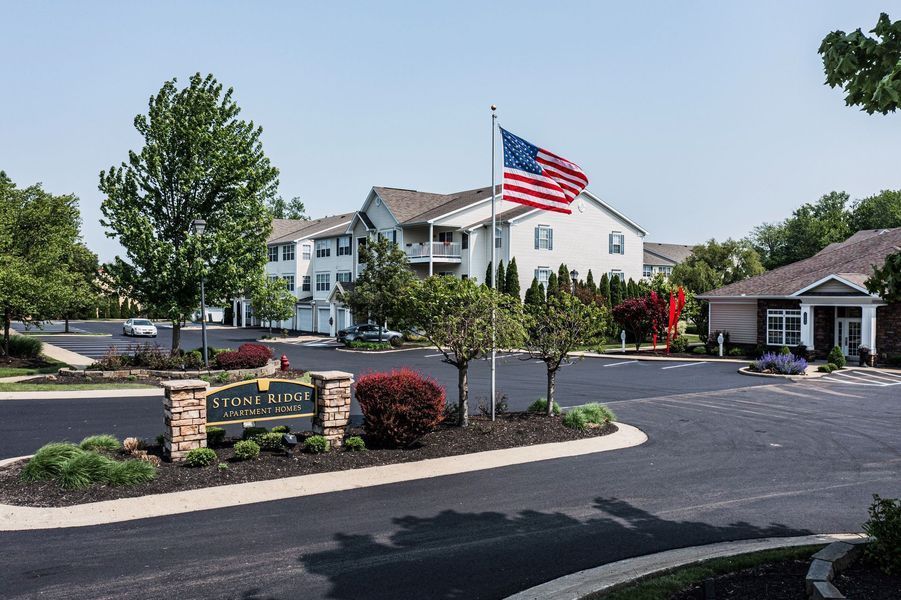 Sign for a senior living community with the American flag in front of a building.