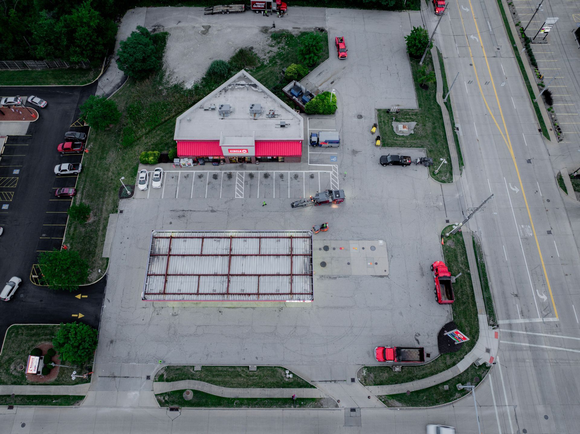 Aerial view of a business with red awning, surrounded by a large parking area and road.