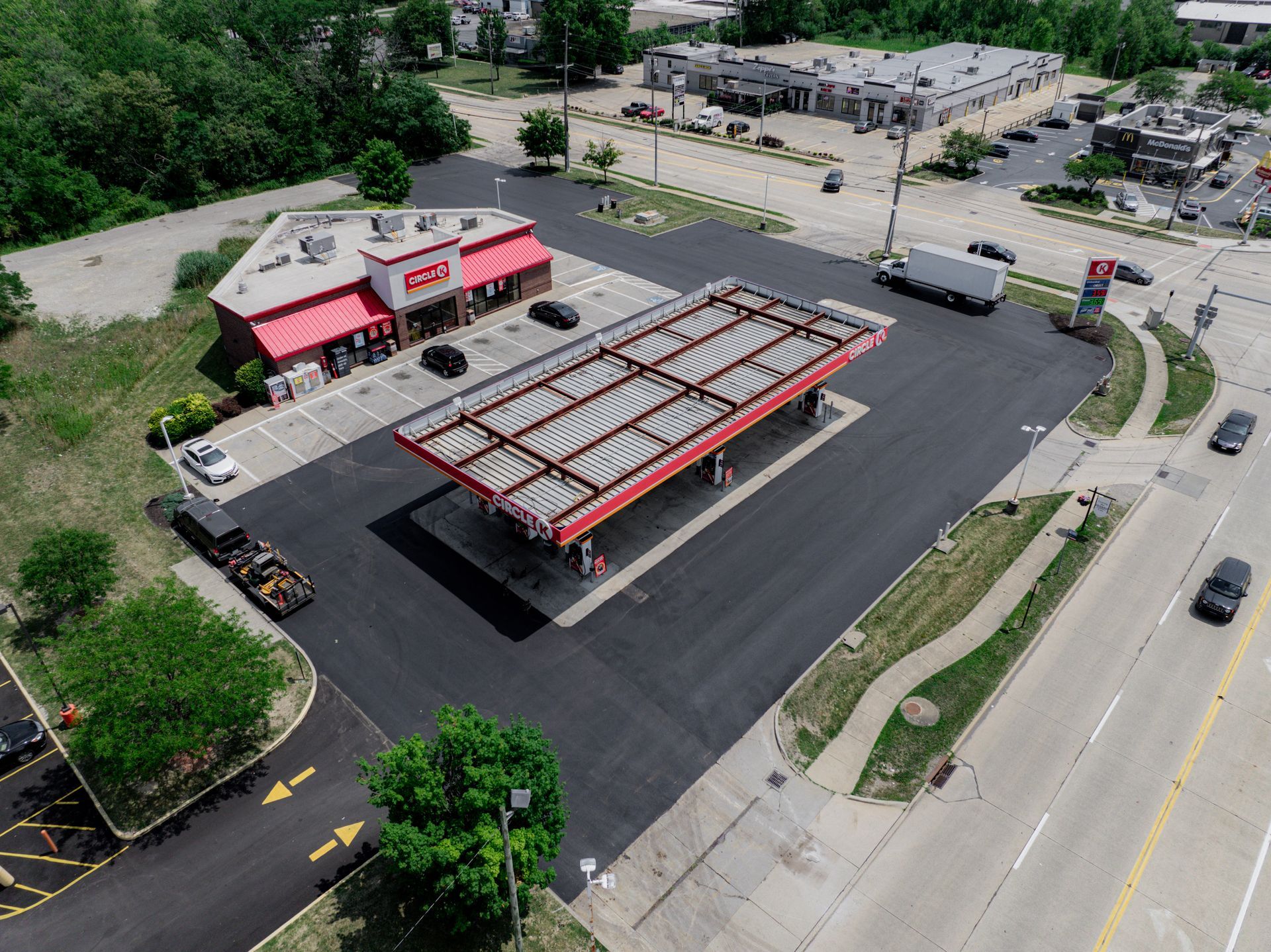 Aerial view of a gas station with a convenience store. The gas station has a red canopy and is next to a road.