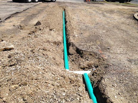 Aerial view of a parking lot filled with cars. A building is on the left, trees on the right.