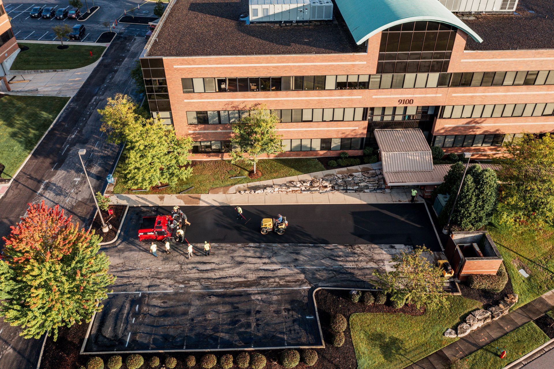 Aerial view of a building with a dark parking lot and a red truck.