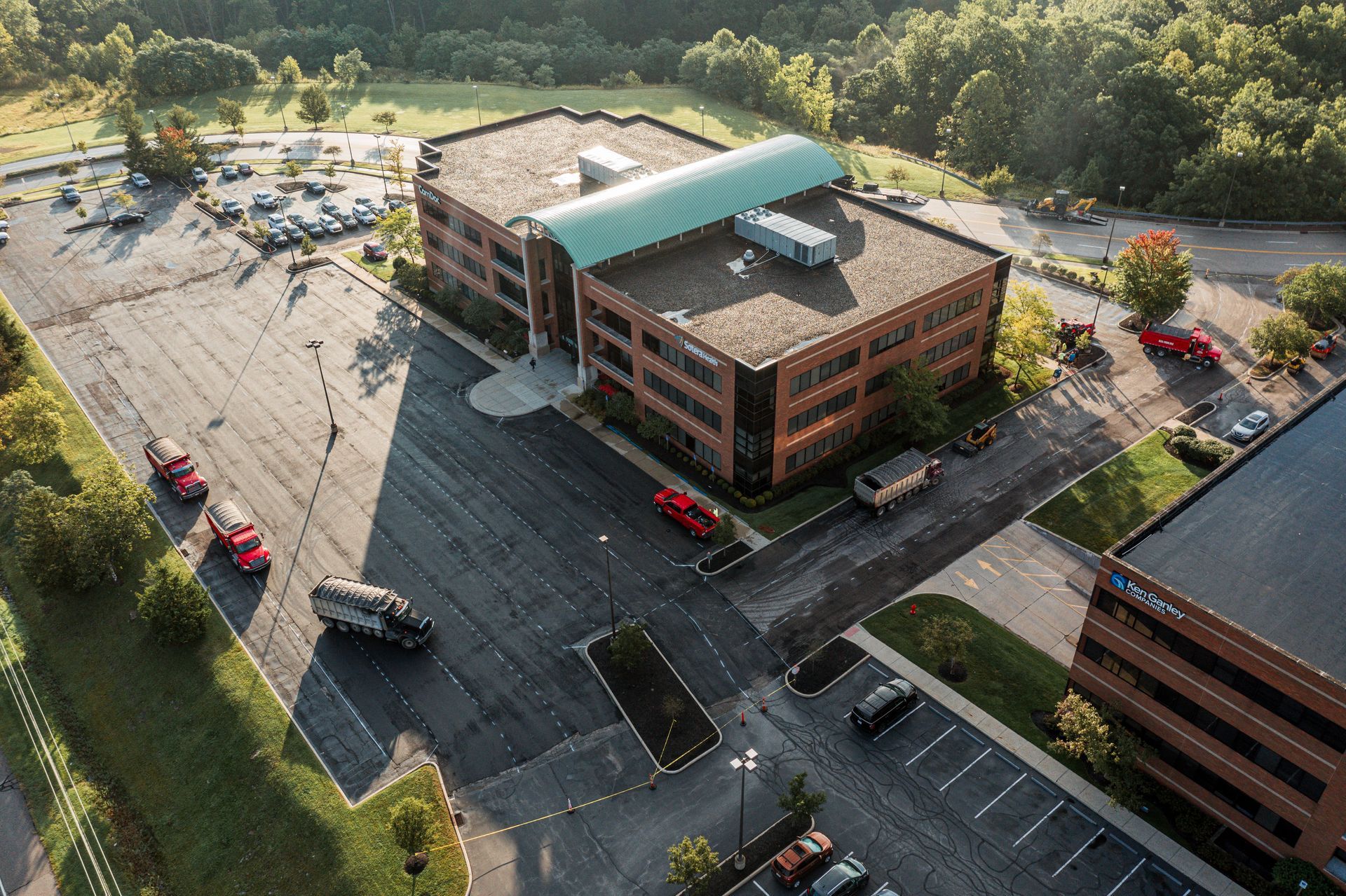 Large beige building with a dark roof and many parking spaces in front; a few cars are parked.
