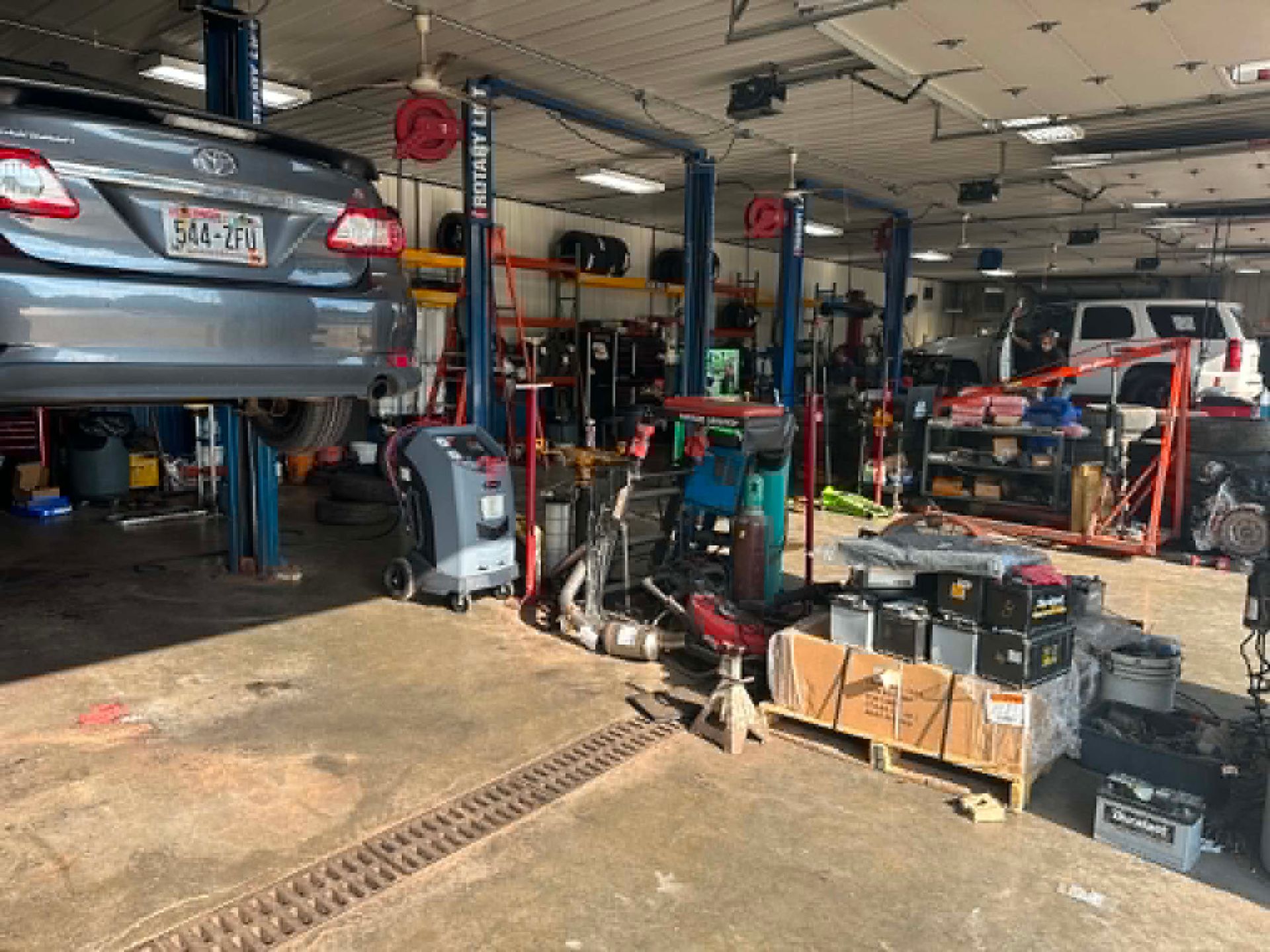 Auto repair shop with a car on a lift, tools, equipment, and vehicles in service bays