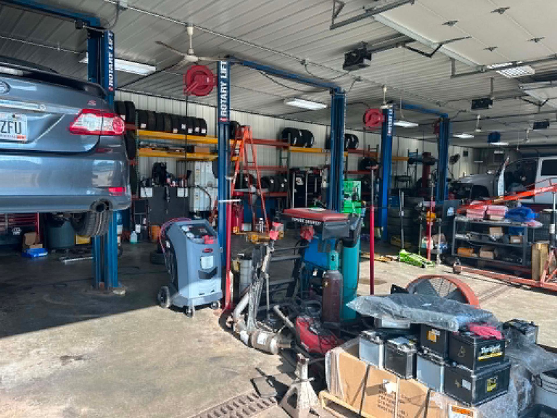 Auto repair shop with cars on lifts, tools, and equipment in a cluttered garage.