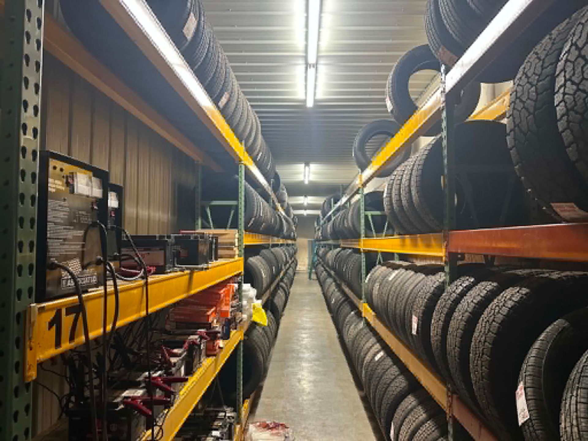 Tire storage aisle in a warehouse with rows of stacked tires on metal shelves