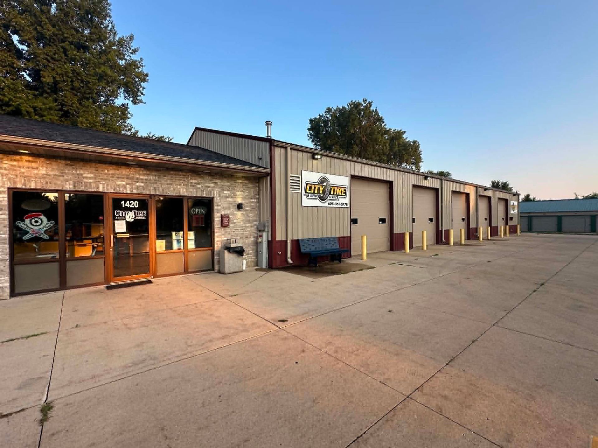 Small row of industrial storefronts at dusk with garage bays and a concrete parking lot