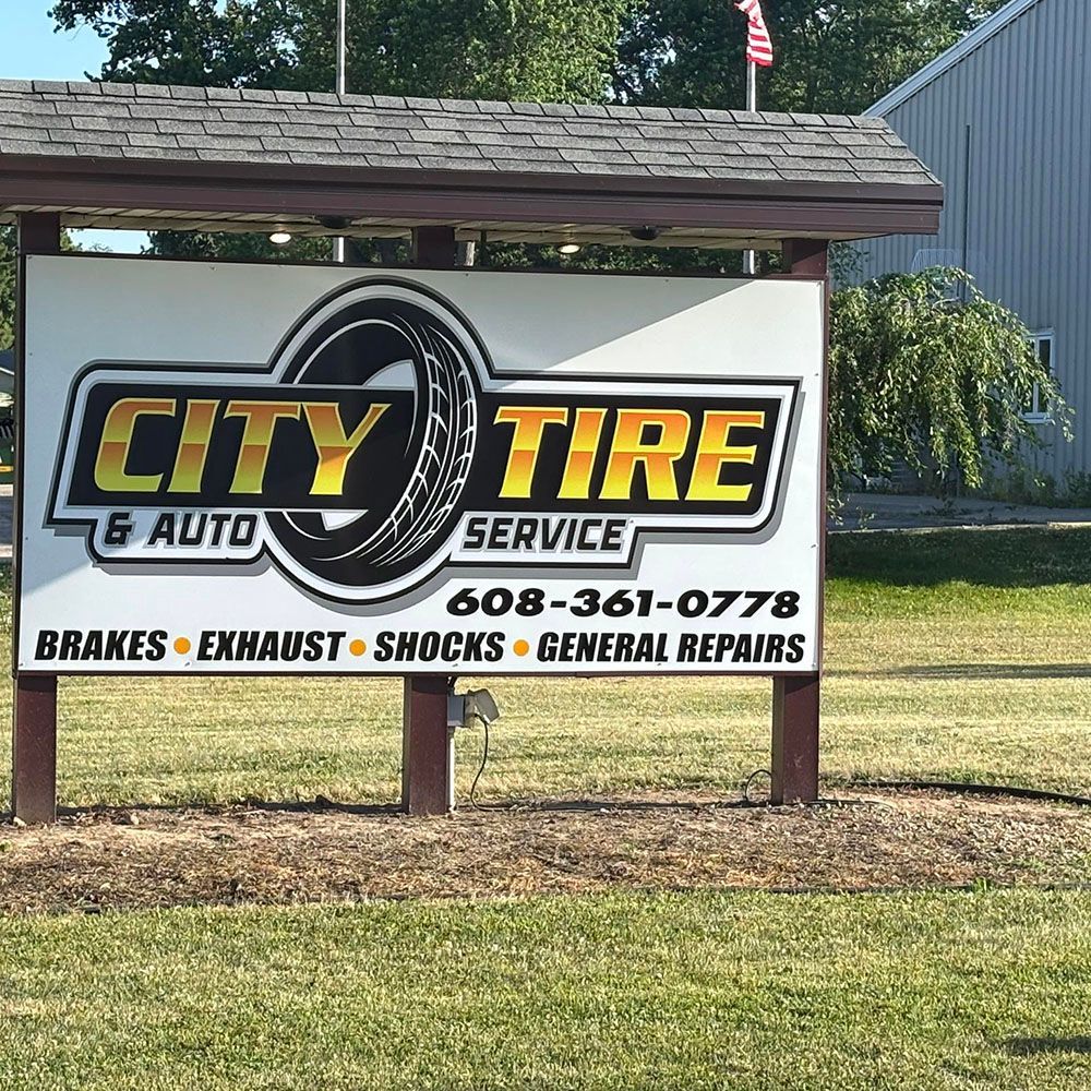 City Tire & Auto Service roadside sign with services and phone number in front of a building