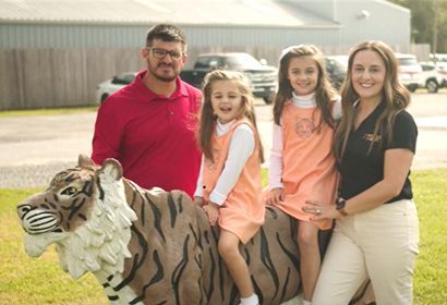A family is posing for a picture with a statue of a tiger.