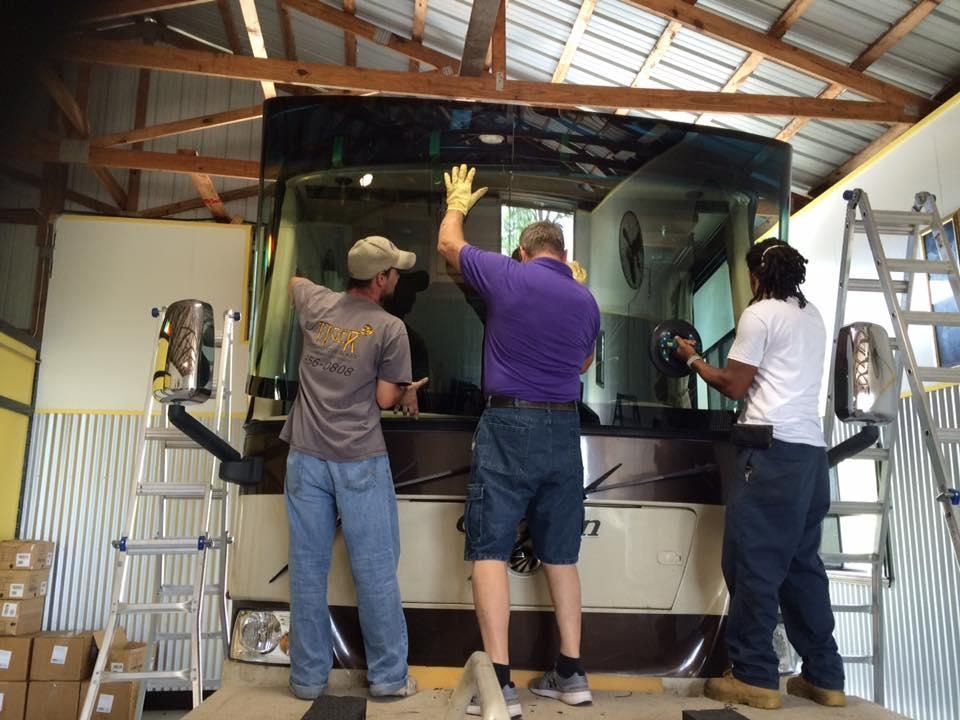 A white boat is parked on a trailer with trees in the background.
