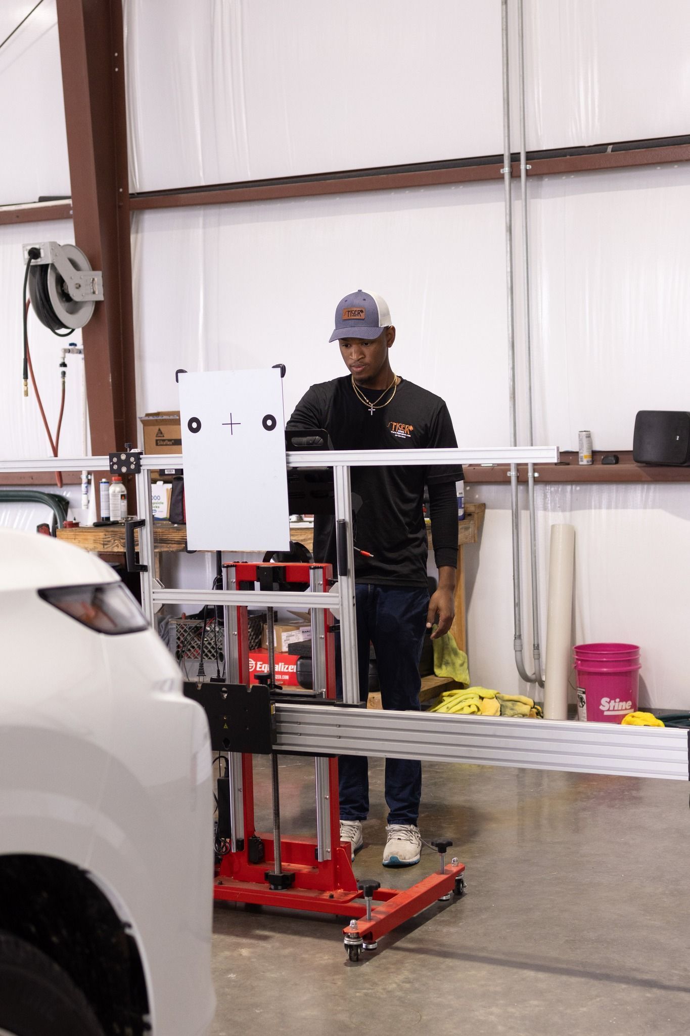 A man is standing next to a white car in a garage.