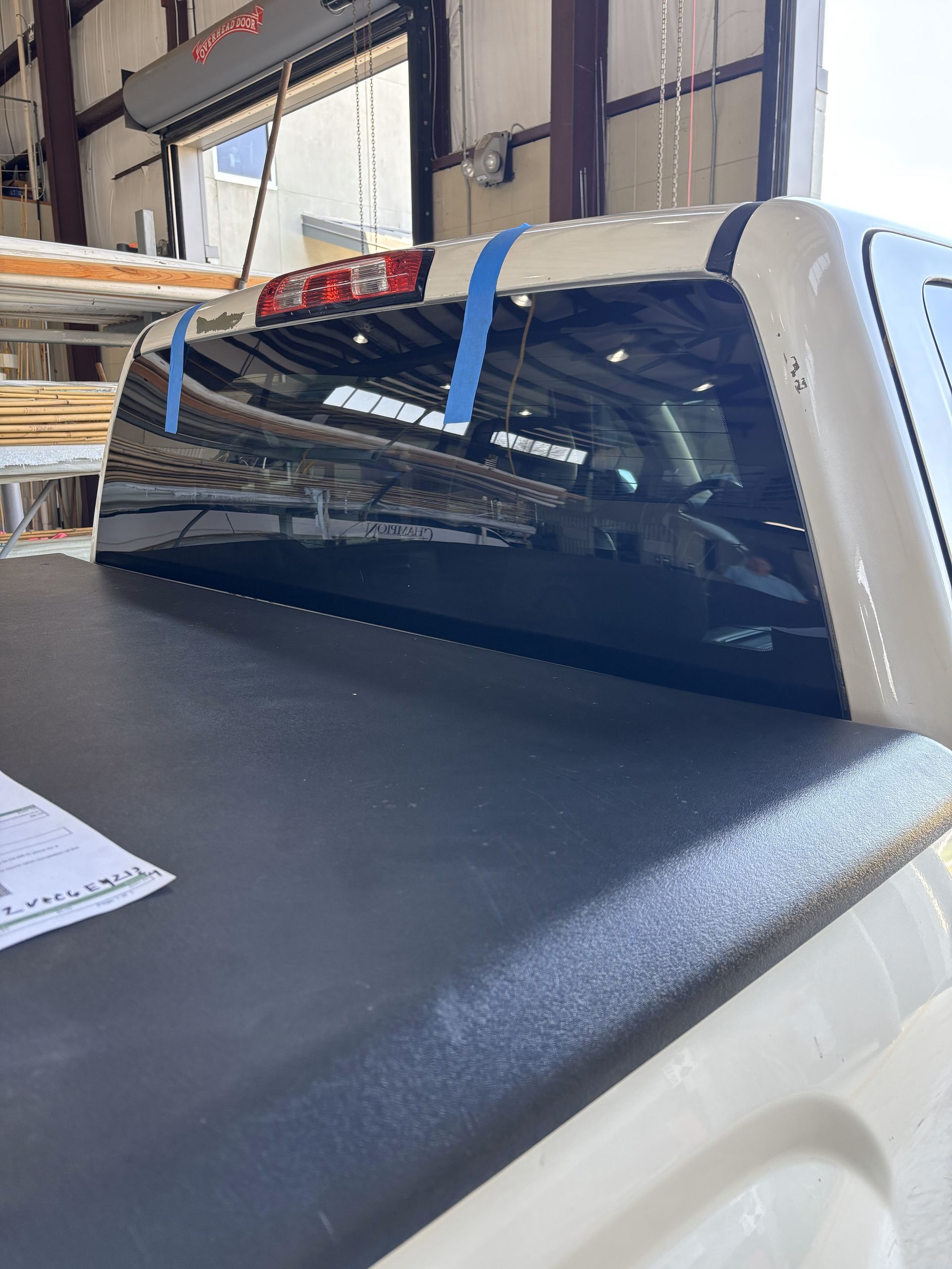 A white truck with a black bed cover is sitting in a garage.
