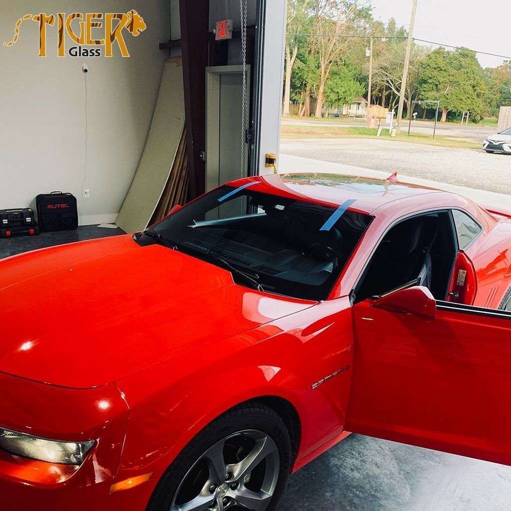 A red car is parked in a garage with the door open