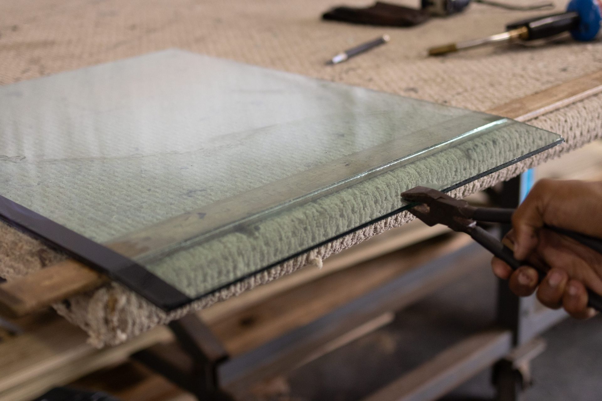 A person is cutting a piece of glass with a pair of pliers