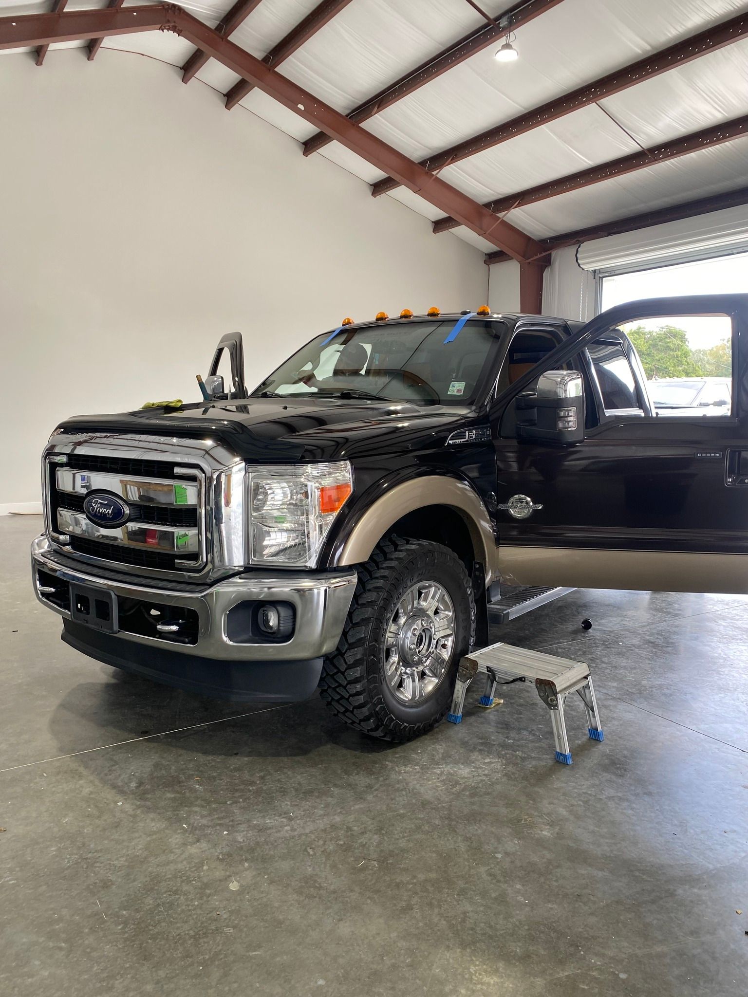 A black ford truck is parked in a garage next to a stool