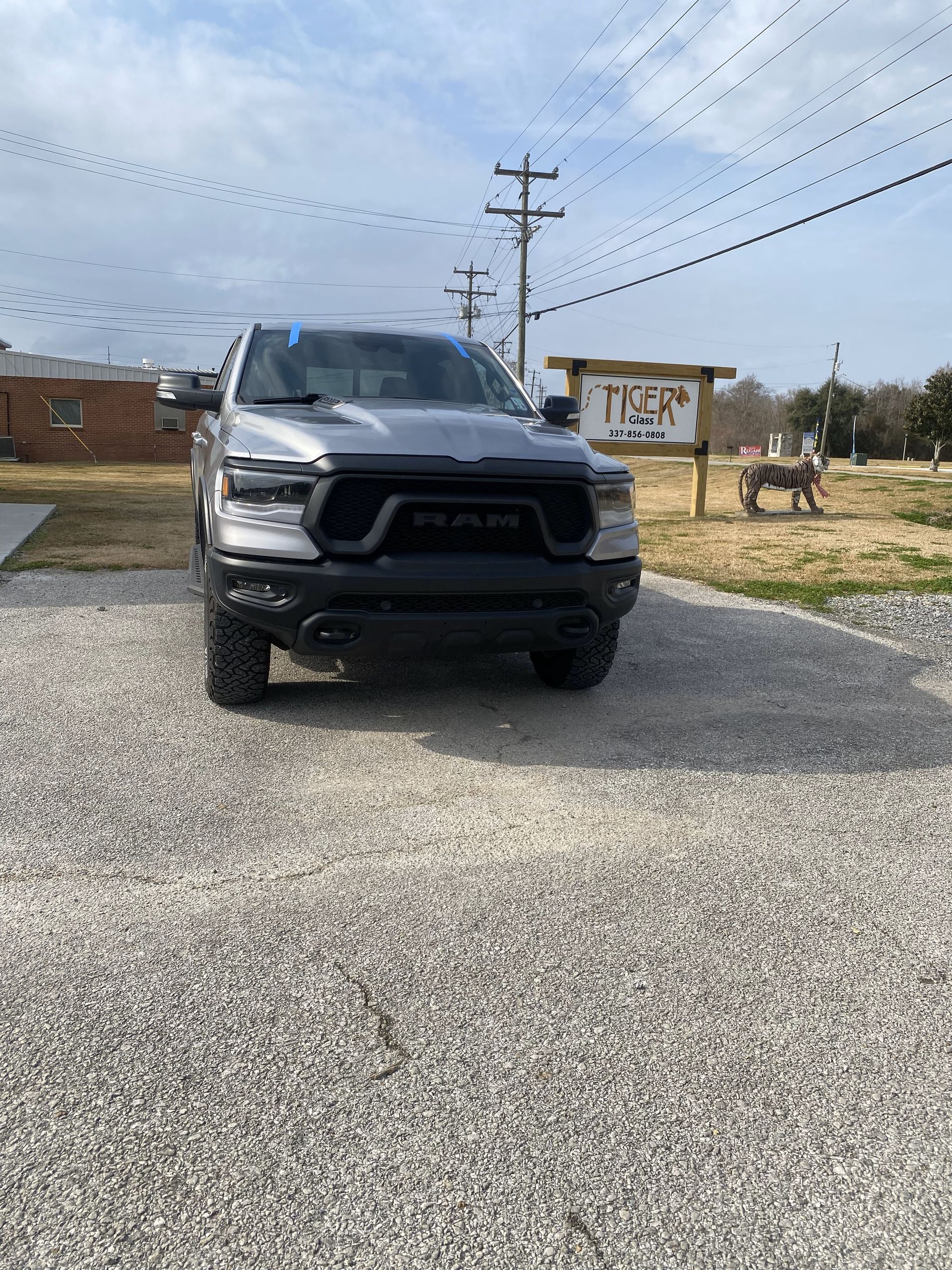 A silver ram truck is parked in a gravel lot.