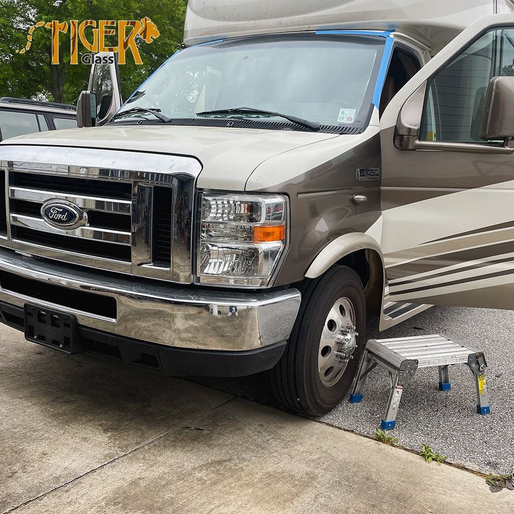 A ford van is parked in a driveway next to a step stool.