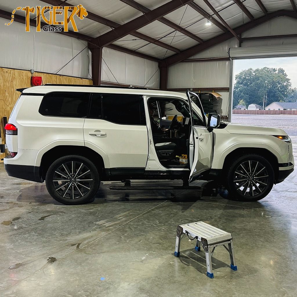 A white suv is parked in a garage with its doors open.
