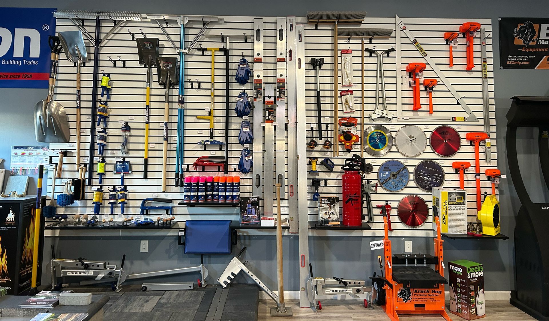 A wall-mounted display rack in a retail store showcasing various construction tools, including saws, blades, and levels.