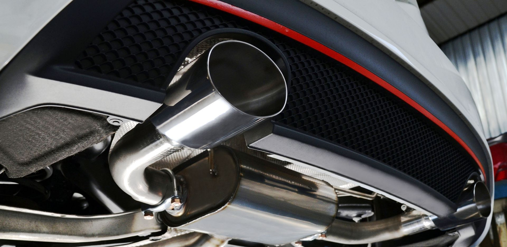 Hands of a person working on a car engine, possibly checking the battery, in a garage.