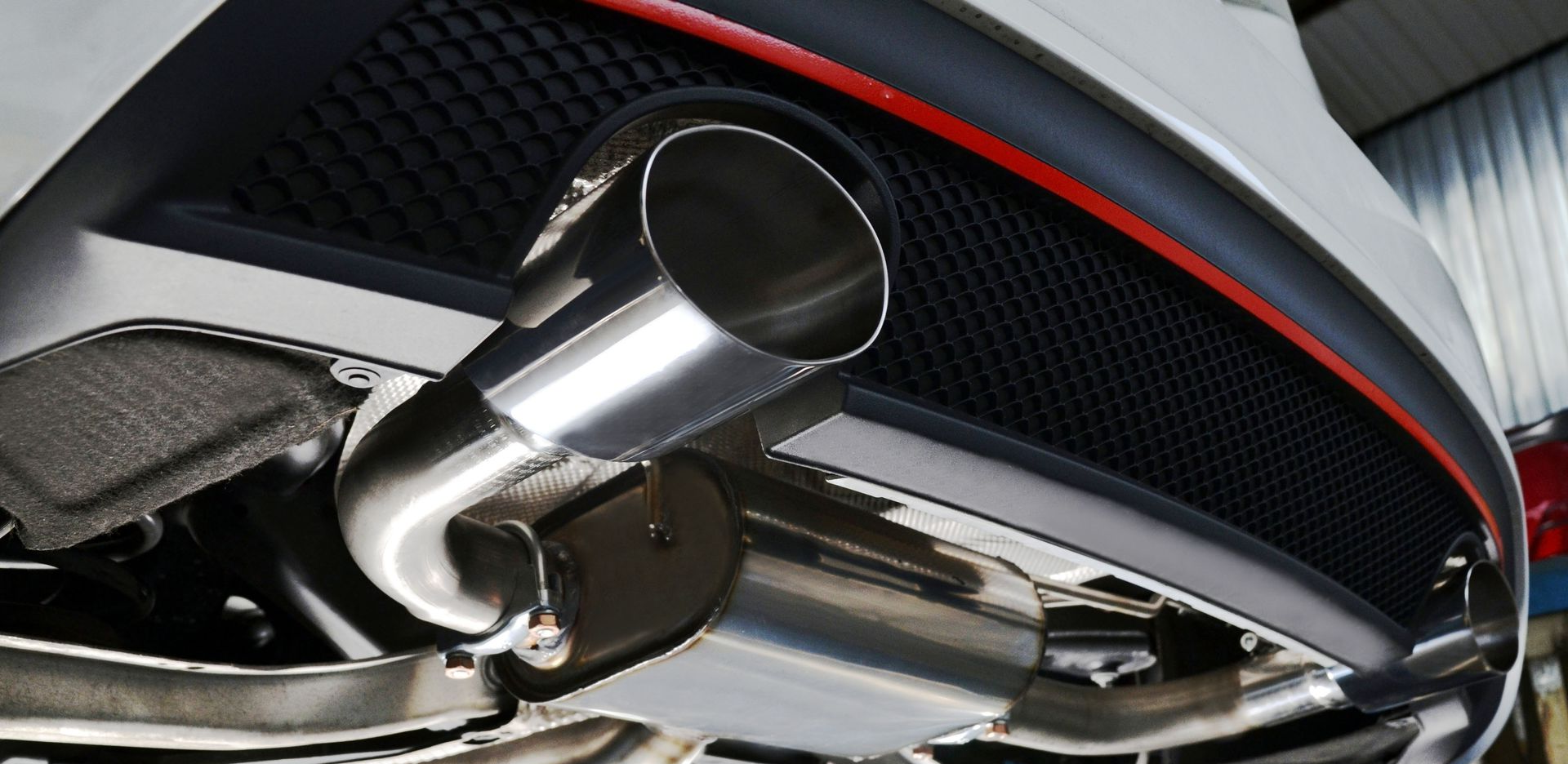 Hands of a person working on a car engine, possibly checking the battery, in a garage.