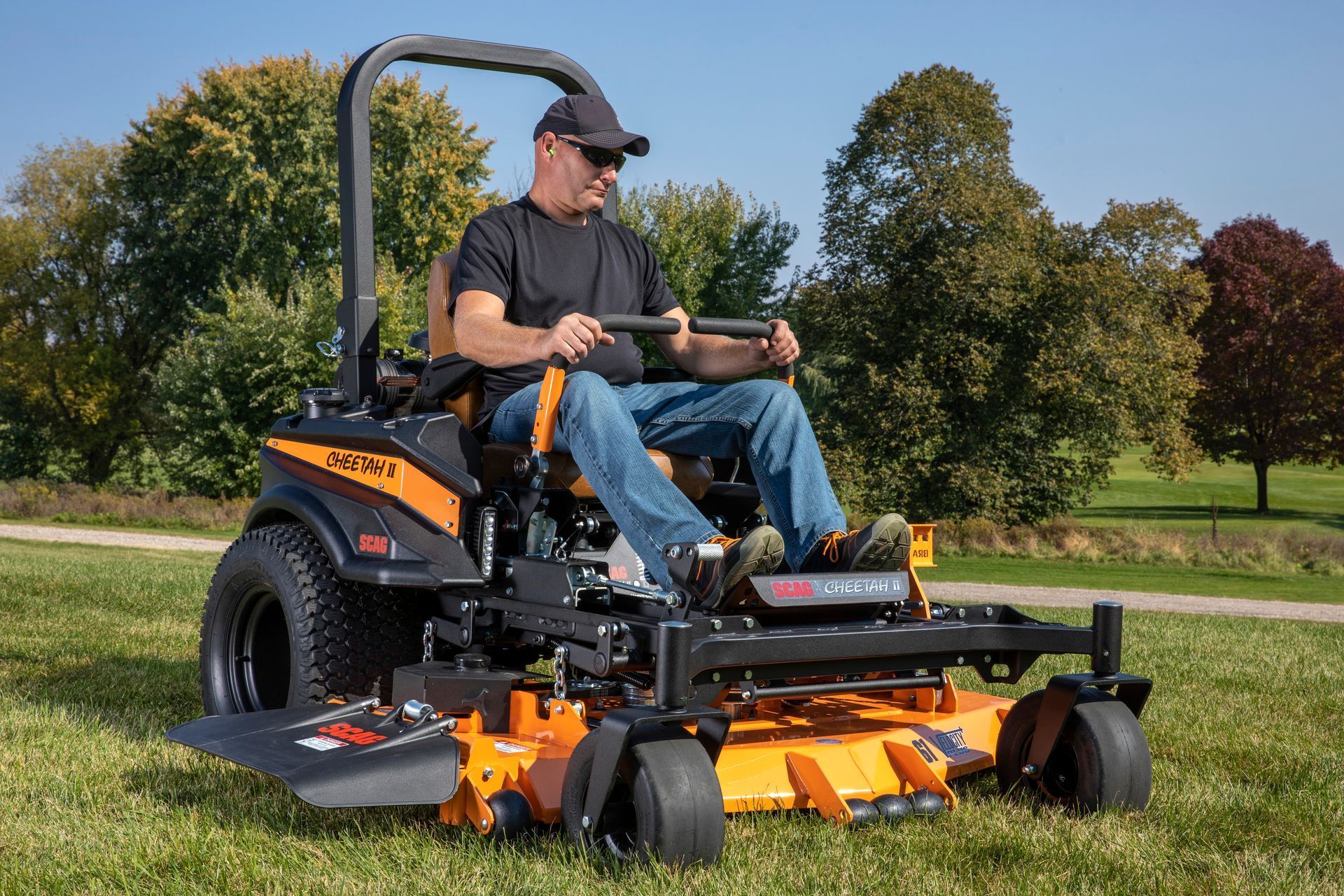 A man is riding a lawn mower on a lush green field.