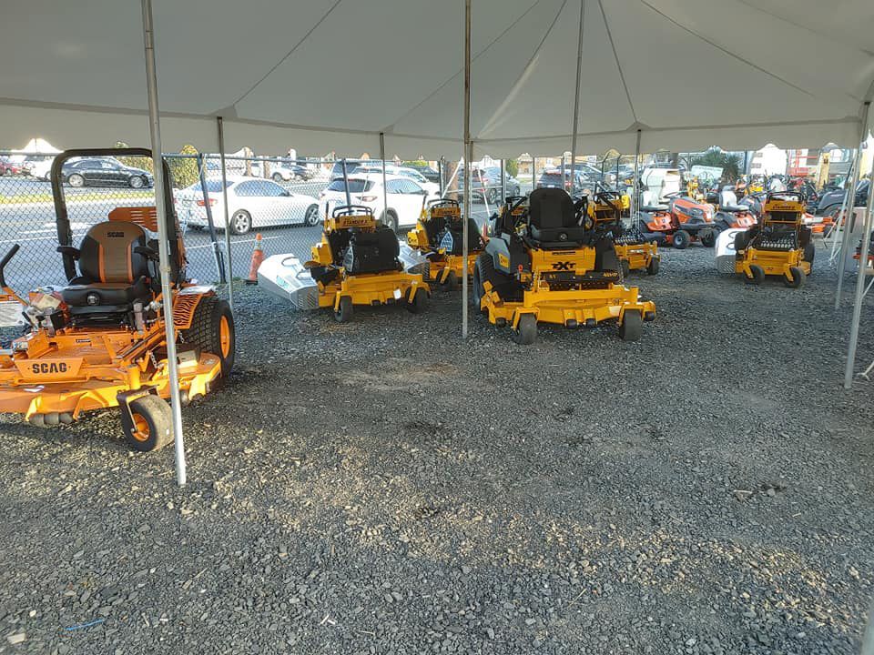 A row of yellow lawn mowers under a tent