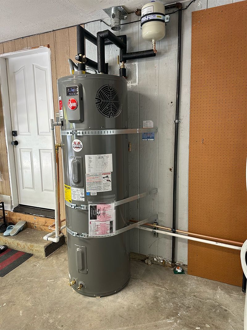 A water heater is sitting in a garage next to a door.