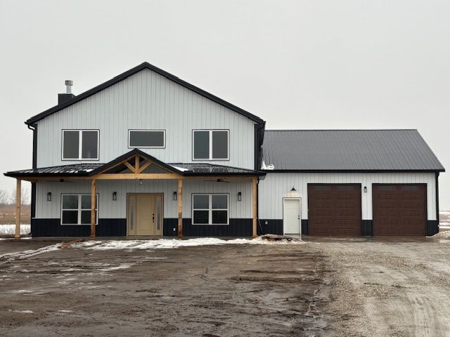 a large white and black house with two garage doors