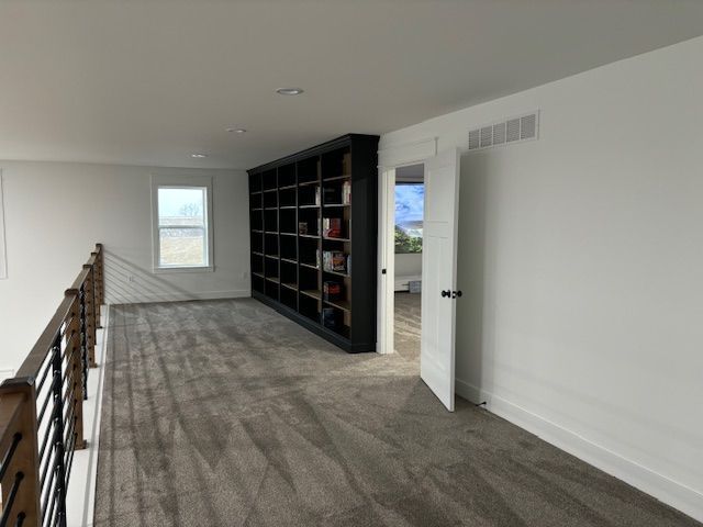 a carpeted hallway with a bookshelf in the middle of it