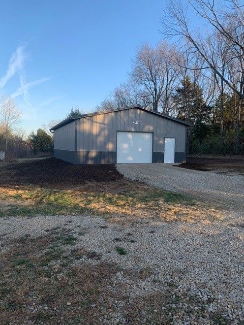 a large metal building with two garage doors is sitting on top of a gravel lot