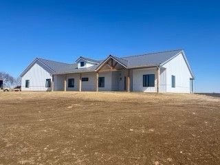 a large white house is sitting in the middle of a dirt field