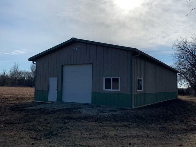 a gray and green building with a white garage door